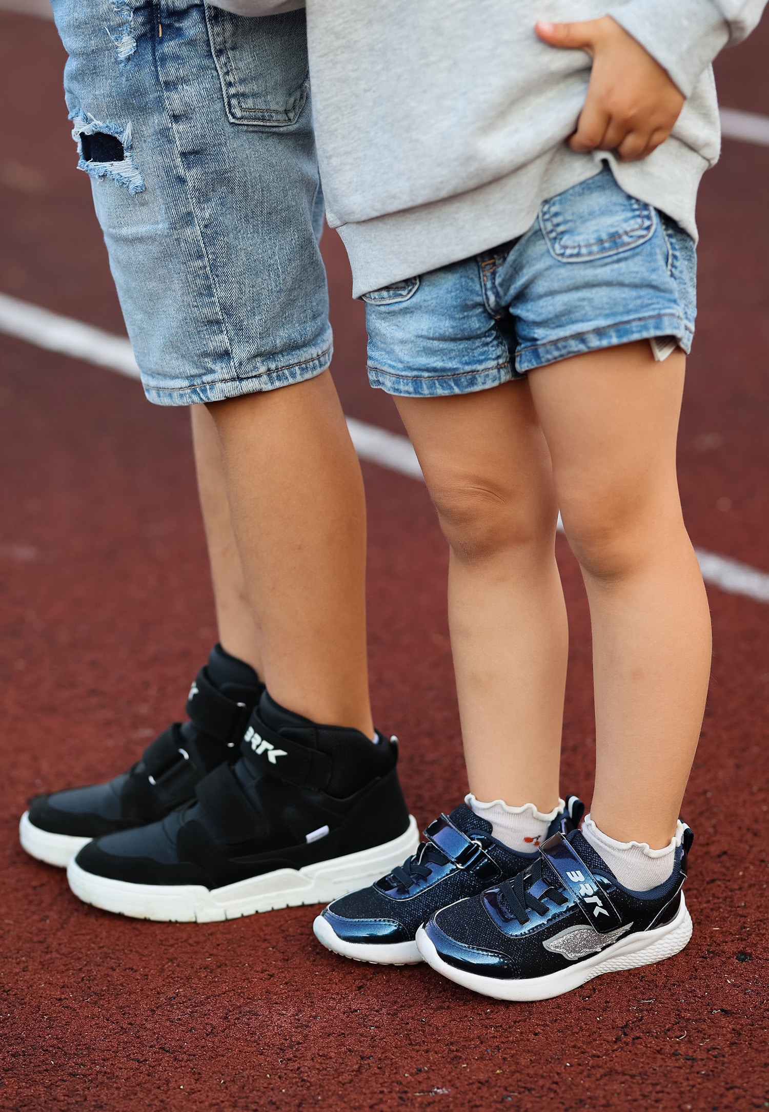 Dzieci w granatowych sneakersach i czarnych trzewikach