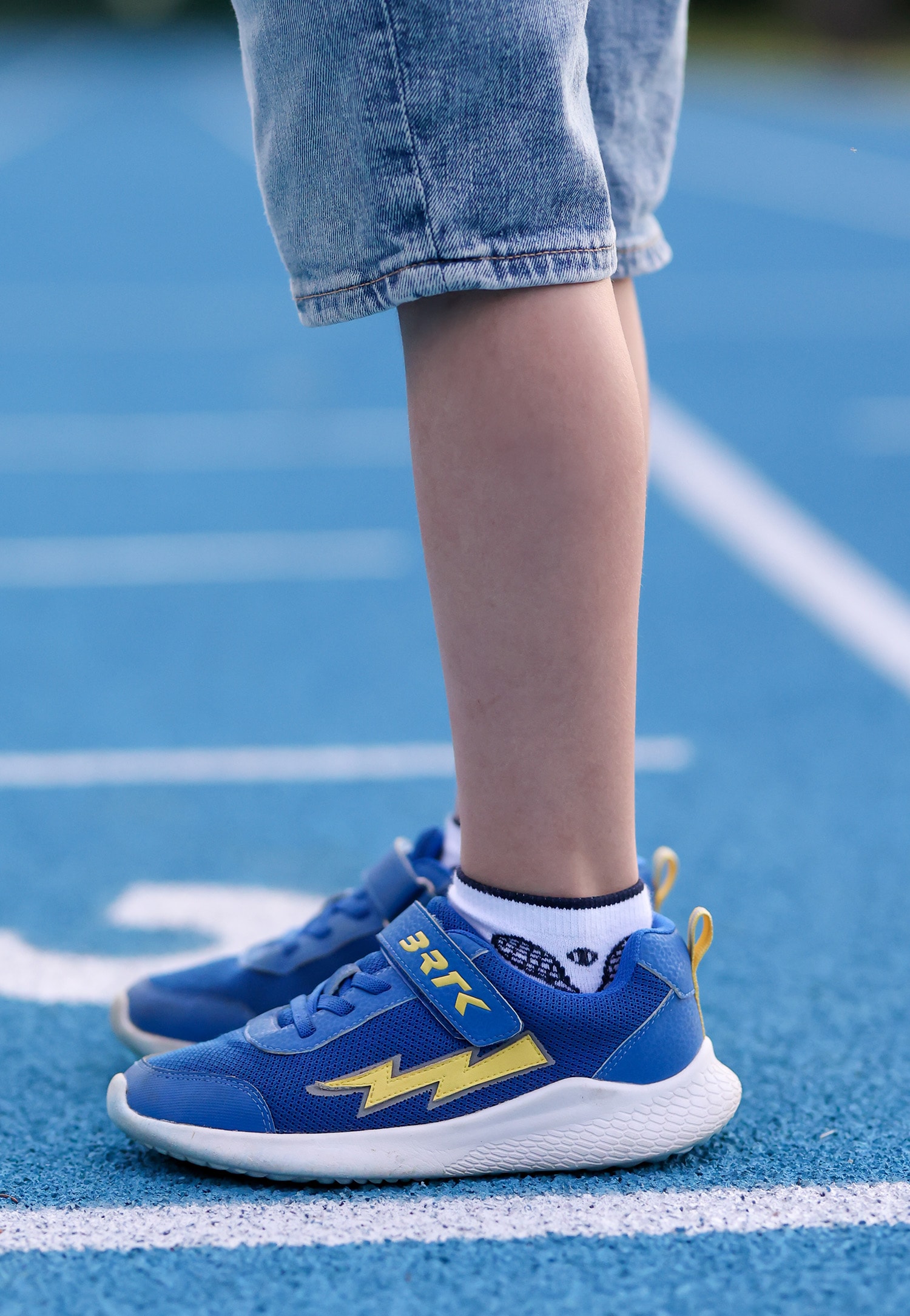 Niebieskie sneakersy sportowe i chłopiec w jeansowych spodenkach