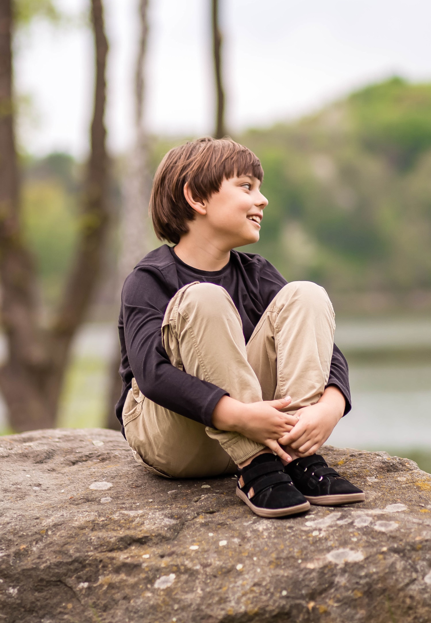 Czarne półbuty chłopiec w beżowych spodniach