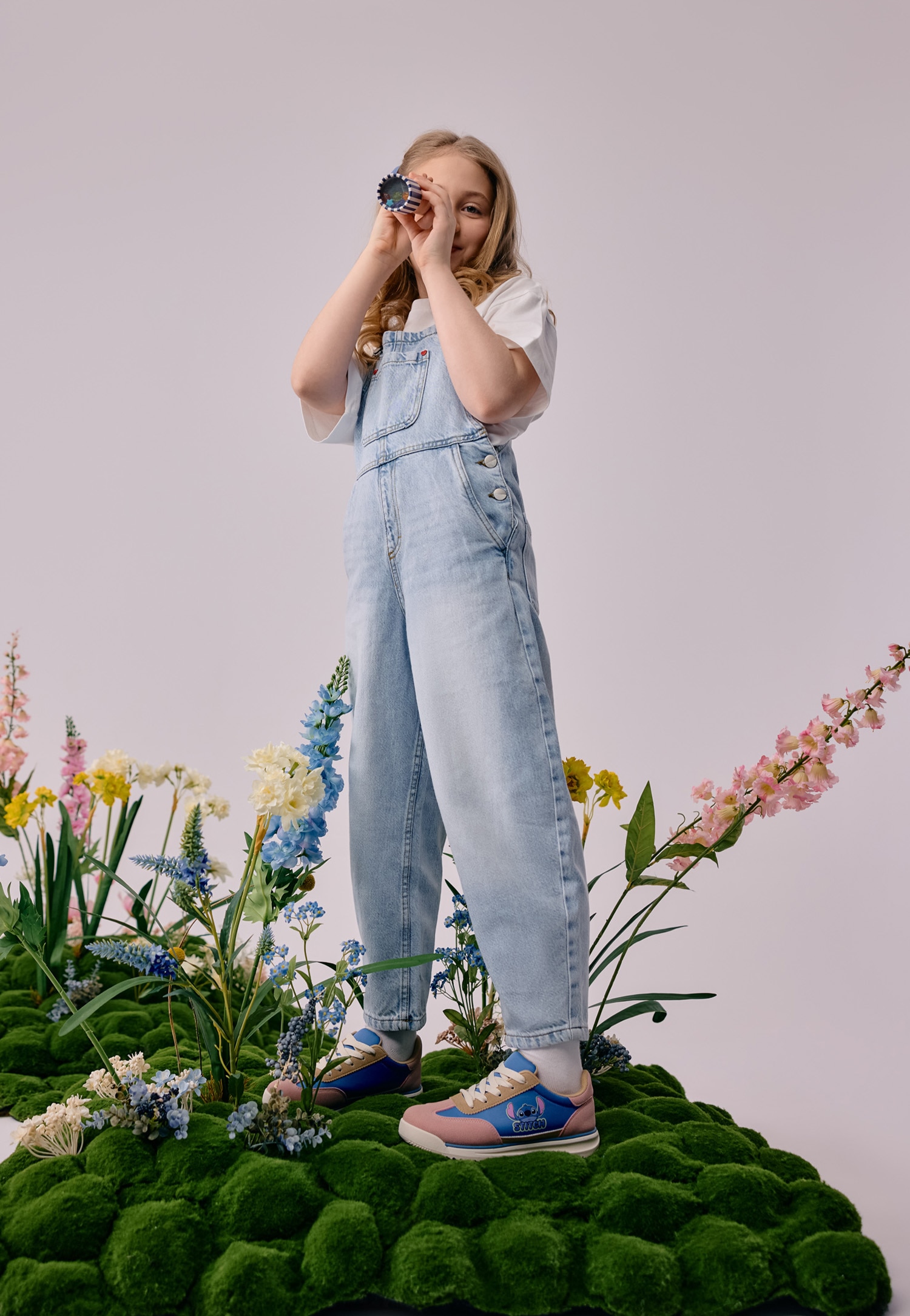 Różowo-niebieskie sneakersy Stitch i dziewczynka w jeansowym kombinezonie