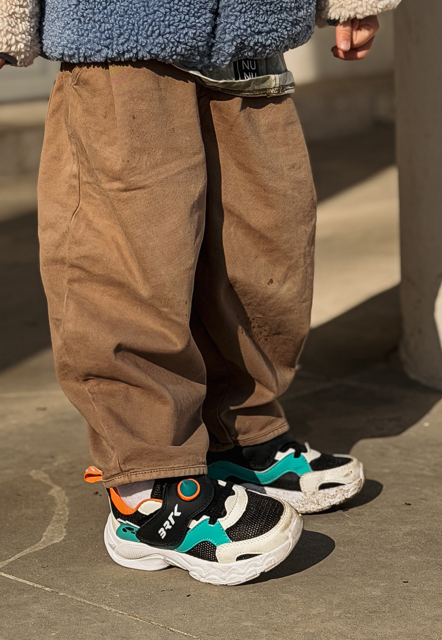 Kolorowe sneakersy i brązowe spodnie