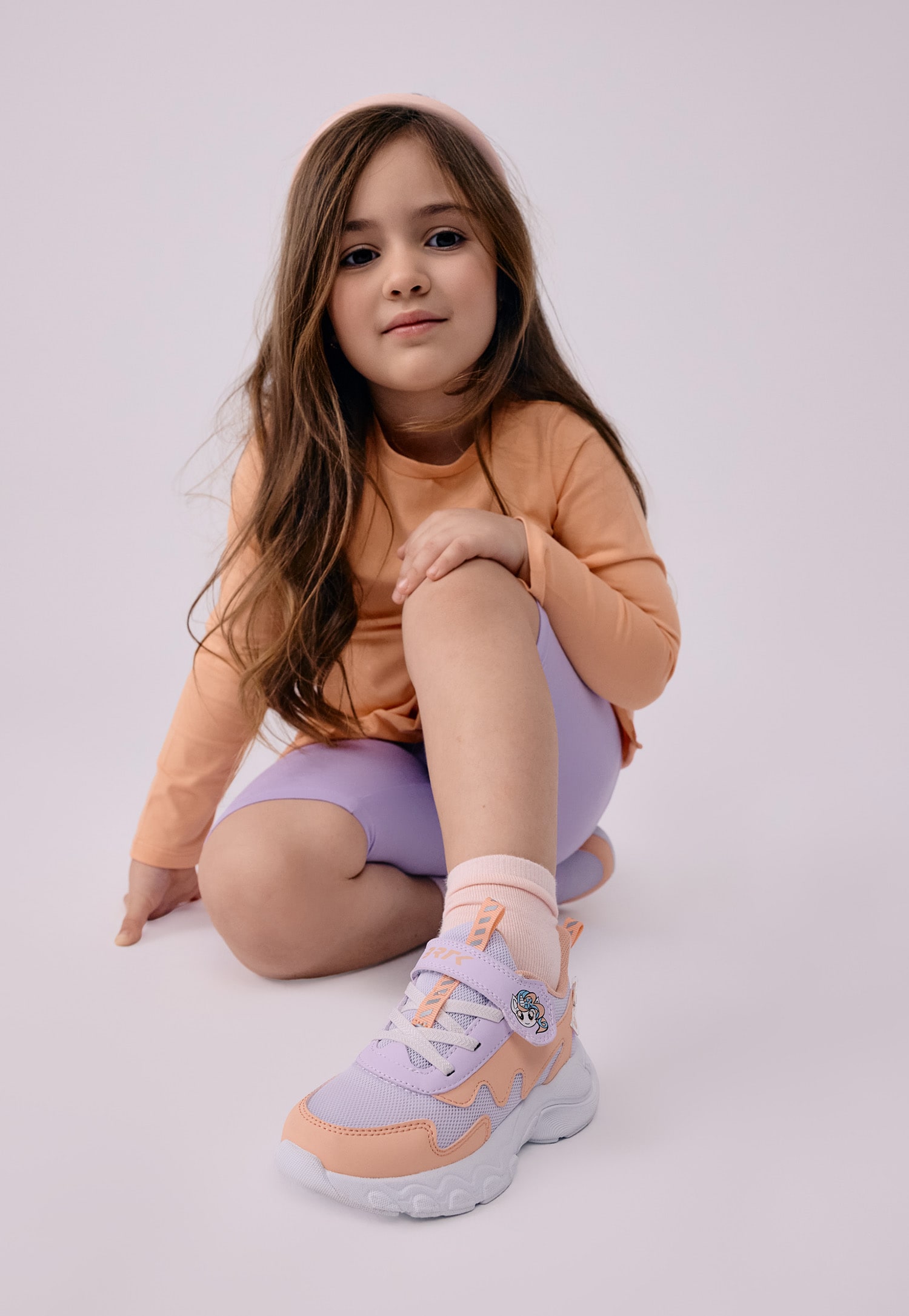 Kolorowe sneakersy i dziewczynka w brzoskwiniowej bluzce