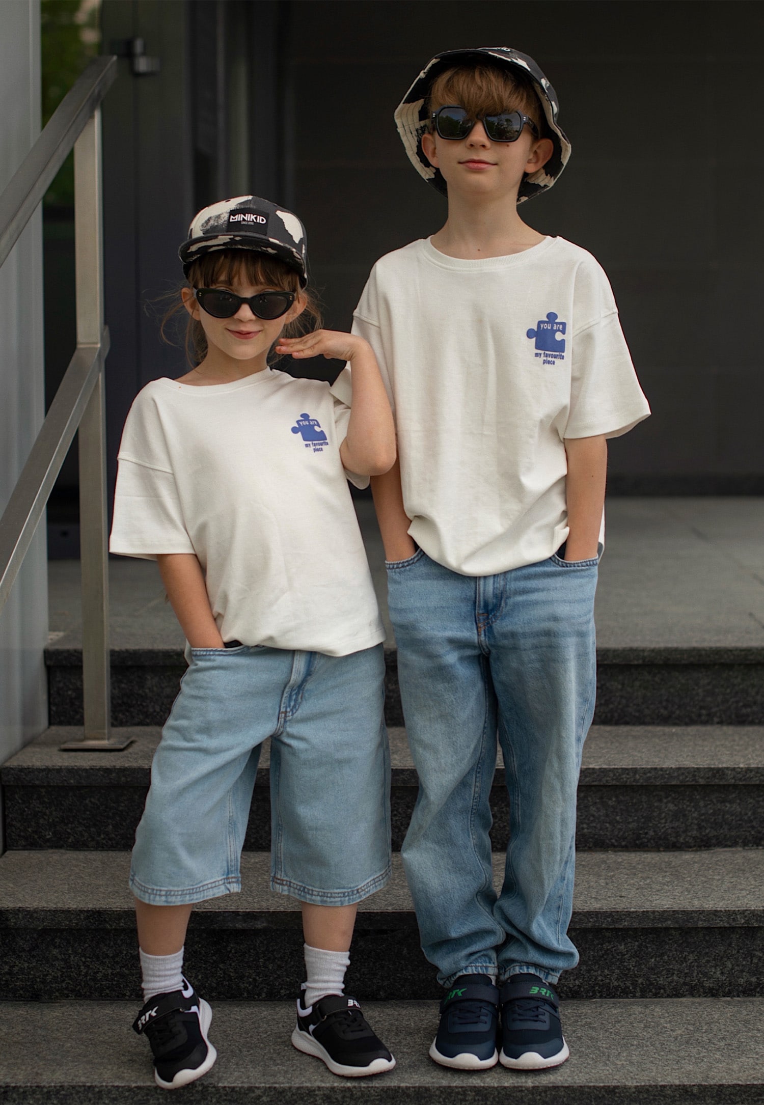 Czarne i granatowe sneakersy i dzieci w jeansach i białych koszulkach